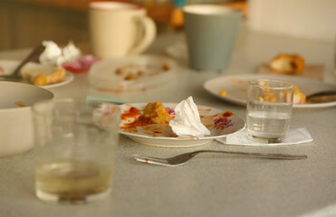 Empty dirty plates with spoons and forks on the table after meal. Banquet ending concept. Unwashed dishes ready to cleaning