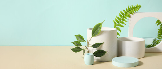 Plaster podiums and green leaves on color background with space for text