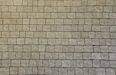 Gray color paving slabs in the pedestrian street sidewalk. Rough cobblestone pattern with many square shaped stones close up