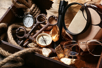 Fototapeta na wymiar Wooden box with travel equipment, golden nuggets and bottle of rum, closeup
