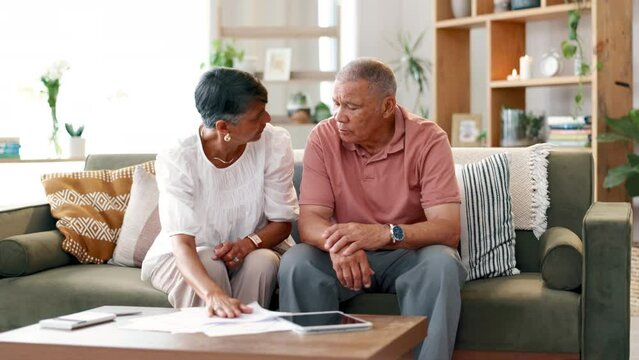 Frustrated, senior and couple with documents on sofa in financial crisis, fight or conflict for bills or expenses at home. Mature man and woman with paperwork in argument, disagreement or stress