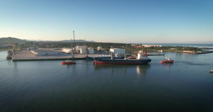 Cargo ship being towed to the harbour by tugboats