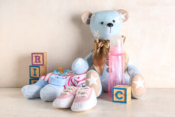 Stylish baby shoes with clothes, toys, bottle of milk and pacifier on grunge white background