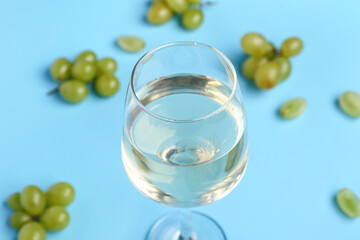 Glass of tasty wine on blue background, closeup