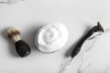 Bowl of shaving foam with razor and brush on grunge white background