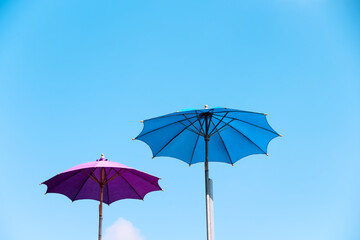 Fototapeta na wymiar Two big umbrella on bright blue sky view outdoor summer background with space