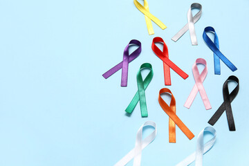 Different colorful ribbons on blue background. Cancer awareness concept