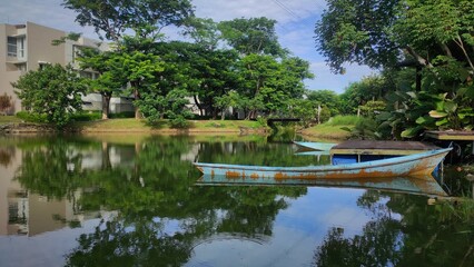 Old wooden boat on the lake of the city park during sunny day 
