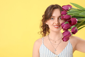 Fototapeta premium Happy young woman with bouquet of beautiful purple tulips on yellow background
