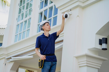 A technician installs a CCTV camera on the facade of a residential building.