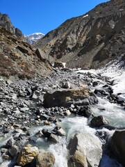 Fototapeta na wymiar A cascading mountain stream winds through a rugged rocky valley