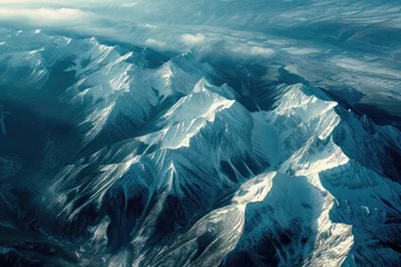 Poster Mountains are covered in snow and are seen from an airplane © Roman