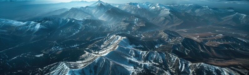 Mountains are covered in snow and are seen from an airplane - obrazy, fototapety, plakaty