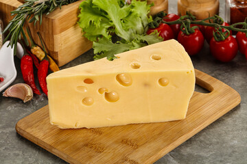 Swiss Maasdam cheese triangle over board