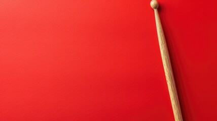 A drumstick lying on a bright red textured background