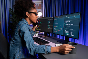 Young African American IT developer concentrating on monitor screen laptop with codding program in...