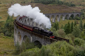 Papier Peint photo Viaduc de Glenfinnan Steam train crosses the Glenfinnan viaduct in the Scottish Highlands. Famous landmark in Scotland. 