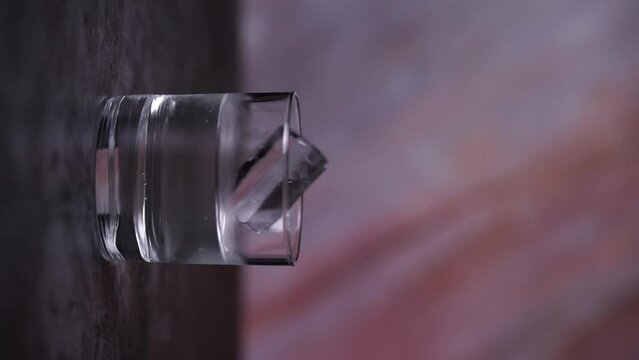 droping an ice cube in a glass of whater vertical video