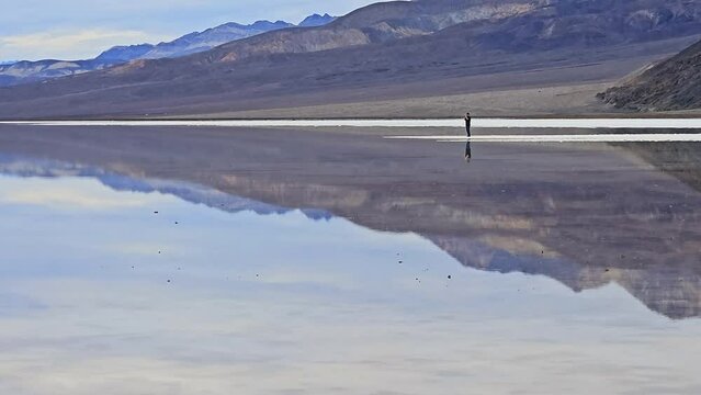Lone unidentifiable tourist takes photos at Badwater Basin during a very rare occurrence of water in Lake Manly. Normally dry, the ancient lake was once 700 feet deep.  It is now the lowest elevation 