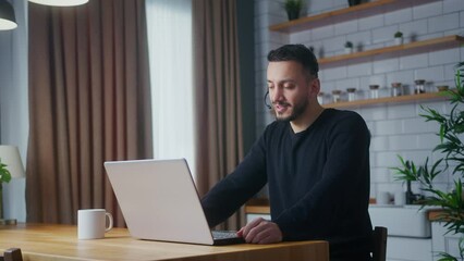 Man representative call center agent in wireless headset helping client with complaints using laptop. Male Operator working at home in kitchen, customer support service on helpline telesales