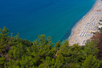 Fototapeta na wymiar Beautiful top view of blue sea ocean water and beach shore with lots many of people tourists, green trees in summertime and bright sunlight sun.Tourism destination,vacation,holiday