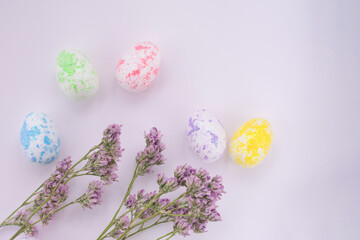 Background with copy space, floral twig branch with little violet flowers and multi colored easter eggs in yellow, pink, green, blue colors.Card,banner,backdrop