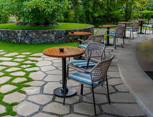 Five sets of outdoor coffee tables each with two simple armchairs and a circular wooden table, all...