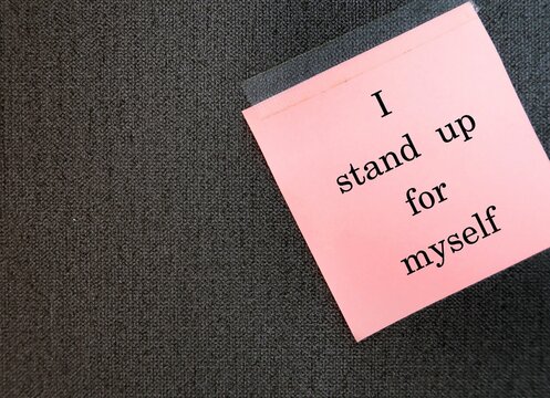 Pink note stick on wallpaper wall with handwritten text I STAND UP FOR MYSELF, positive daily affirmation to boost self esteem - uplift and powerful self talk statement to feel empowered and confident