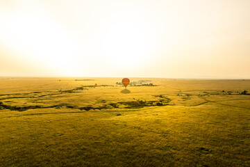 Colourful hot air balloon flying over Masai Mara National Reserve at sunrise, Kenya.