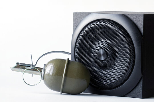 Hand grenade, next to a black audio speaker system. Create a visual metaphor for powerful sound or explosive audio and explosive sound. Copy space. Photo