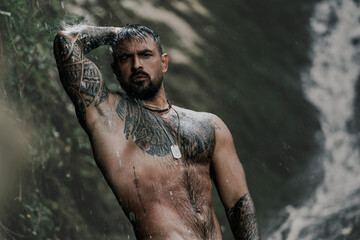 Naked sexy man at a tropical waterfall, Bali. Man relaxing with freedom. Strong fit Man in...