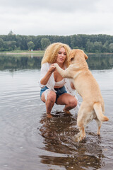 Young woman playing with her labrador retriever dog in river.
