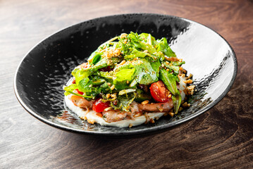 Fresh salad plate with shrimp, tomato, spinach in plate on wooden table background