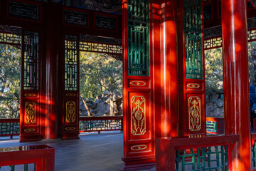 An inside look of a traditional Chinese gazebo with open doors and walls, dominant sharp red and a little of jade green and gold sculptures.