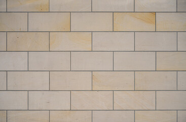 texture of a tiled beige stone wall as background, natural stone wall texture as background. Close-up of a wall clad in limestone	