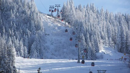 Cable cars going up and down the snowy ski slope in mountain resort during winter