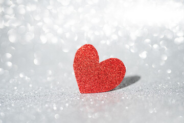 Red heart on a silver background with beautiful bokeh. Valentine's Day is the feast of lovers.