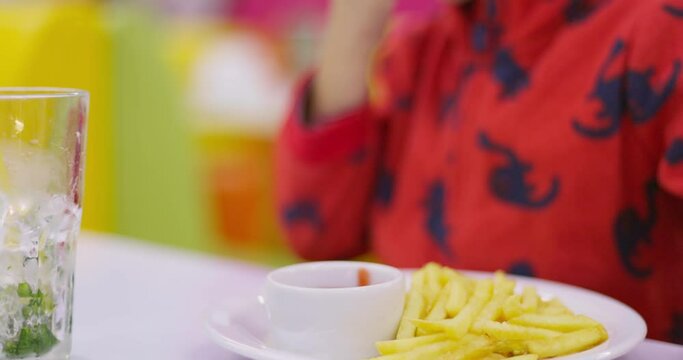  Childs hand dipping a french fry into ketchup with colorful background