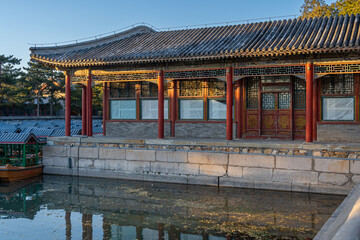 A waterfront boat station building inside an ancient Chinese palace complex with stone foundation and worn out weathered red entrance door.