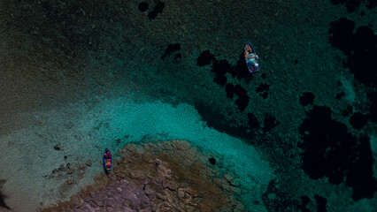 Obraz premium Aerial view of Cala Sapone, S. Antioco bay in Sardinia. Crystal clear sea, moored boat and white sand.