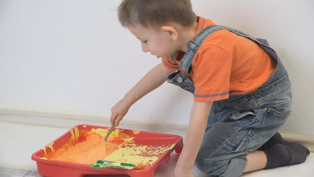 Little boy preparing to paint the wall with colors