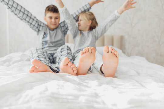 the bare, clean feet of two children, offspring, lying side by side under the same blanket on the bed. morning relaxation, cozy rest. cute pictures of baby feet