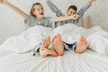 Obraz na płótnie Canvas the bare, clean feet of two children, offspring, lying side by side under the same blanket on the bed. morning relaxation, cozy rest. cute pictures of baby feet