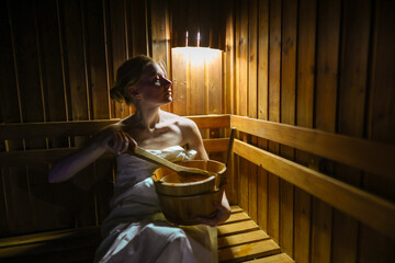 Young woman is taking a steam-bath at sauna