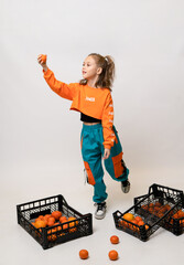 Girl in bright clothes on a white background with oranges