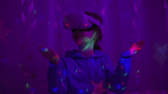 Girl Using Virtual Reality Headset And Looking Around At Interactive Technology With Colorful Illumination. VR Entertainment Immersive. Girl Wearing VR Headset in World of Virtual Reality Interacting.