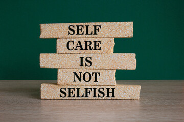 Self care is not selfish symbol. Concept words Self care is not selfish on brick blocks. Beautiful wooden table green background. Business do you know your limits concept. Copy space.