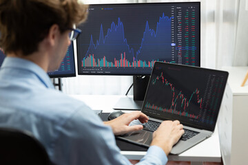 Working young business trader typing, focusing on laptop in market stock graph data investment in real time laptop in screens. at modern office, analyzing dynamic financial exchange rate. Gusher.