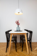 Interior of a modern dining room with black chairs and a table lamp