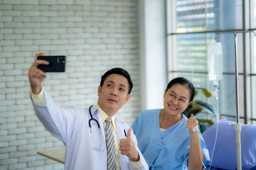 Doctor takes selfie with patient When the patient's symptoms improve and he will be able to return home.